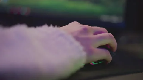Hand on mouse in fluffy sweater with soft colorful lighting at desk setup Stock Footage 307458812