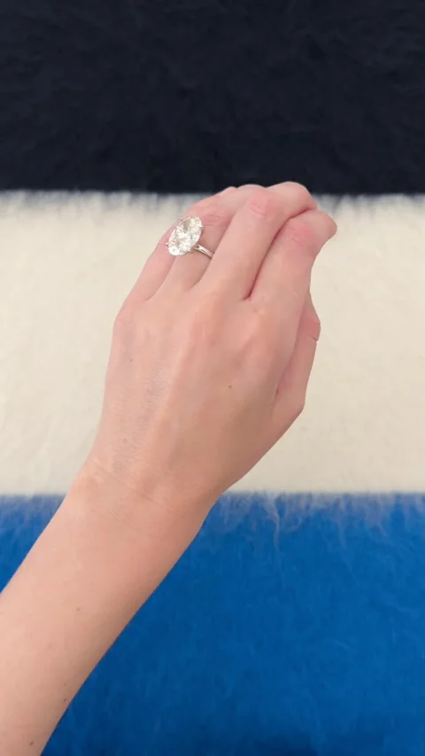 Hand movement with large oval diamond engagement ring on blue background 스톡 동영상 328251115