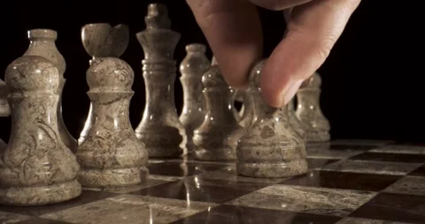 Hand moves chess piece on marble board in a quiet indoor space Stock Footage 339303588