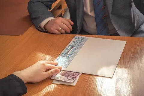 Hand moves a folder with documents and euro bills inserted into it across a.. Stock Photos