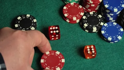 A hand moves to place poker chips and dice on a green felt table, illustrating a Stock Footage 337430500