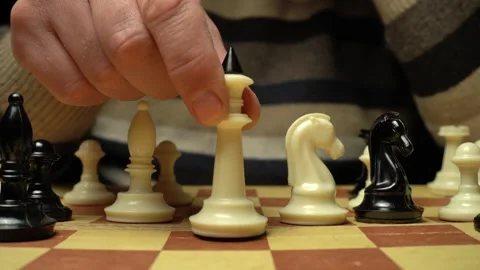 Hand moves white chess piece on board, capturing attention with strategic play Stock Footage 332649381