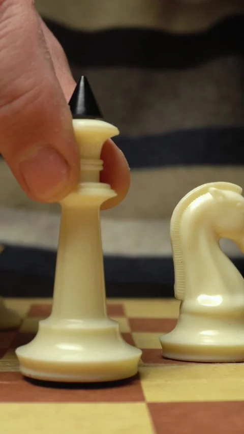 Hand moves white chess piece, a rook, towards the center of a chessboard with a Stock Footage 339366854