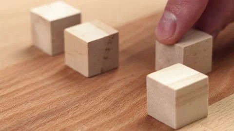 Hand moves wooden block, stacking geometric wood cubes in a row Stock Footage 204723991