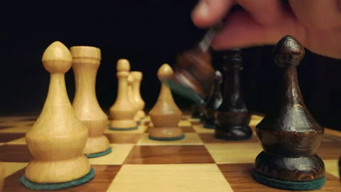 Hand moving black pawn while camera zooms in between two rows of chess figures o Stock Footage 149354579