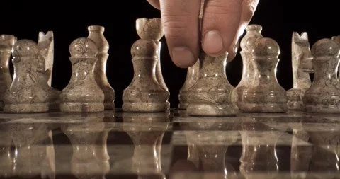 Hand moving a chess piece on a chessboard with reflective surface Stock Footage 340482469
