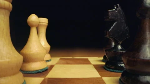 Hand moving chess tower while camera zoom out between chess pieces on wooden che Stock Footage 149365069