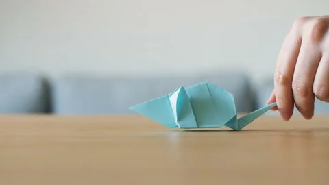 A hand moving a cute stylized blue handmade Origami Mouse on a wooden table. Stock Footage 143810344