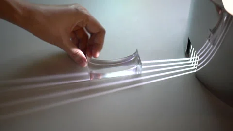 Hand moving transparent prism showing light distortion to create spectrum Stock Footage 162895811