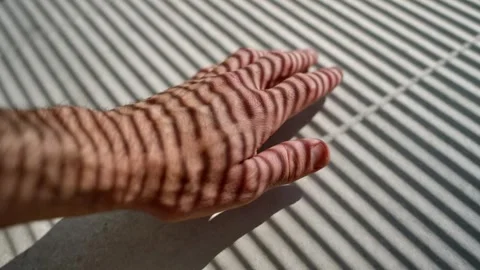 Hand moving on wall or floor with shadow of window blinds creating line pattern Stock Footage 311709527