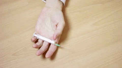 Hand of narcotized man with syringe falls on the floor Stock Footage 233456400