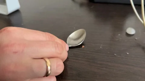 Hand near spoon and small tablet on table surface 動画素材 336976471