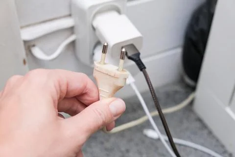 Hand need to plug a socket into a overloaded outlet with an extension and man Stock Photos