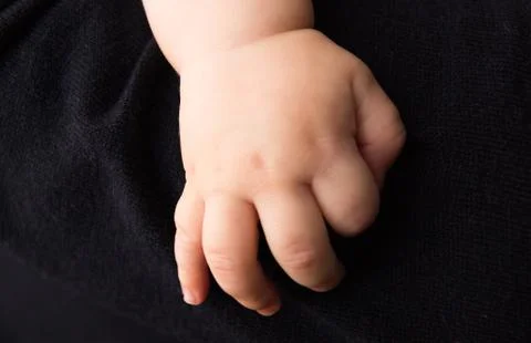 Hand newborn on dark background Stock Photos