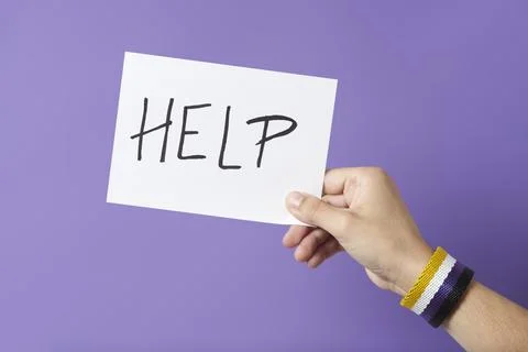 Hand with a non binary gender flag bracelet holding a paper with a message: h Foto stock