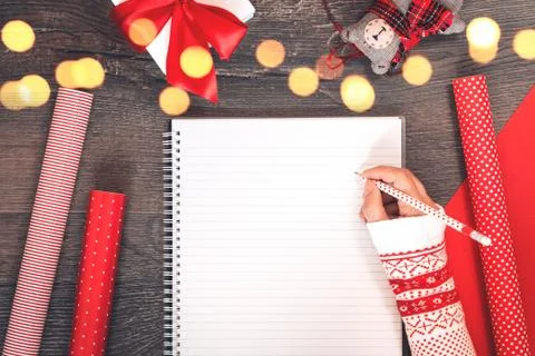Hand with notepad Christmas tree and red gift wrapping paper Stock Photos