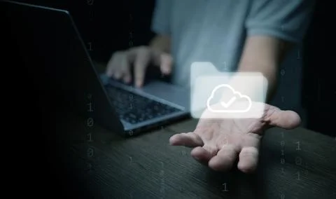 Hand offering cloud folder icon on laptop represents digital files, paperle.. Stock Photos
