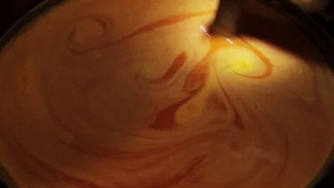 The hand of an old witch is stirring a orange foaming potion in a bubbling vat  Stock Footage 116803255