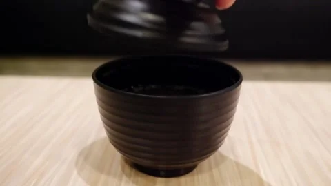 Hand open the lid of the black broth cup and White smoke floating on table Stock Footage 134825174