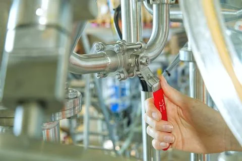 Hand open red gate valve to prevent reverse flow of water in factory and Stock Photos