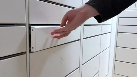 A hand opening an automated parcel locker to collect a delivery, highlighting a Stock Footage 346466539