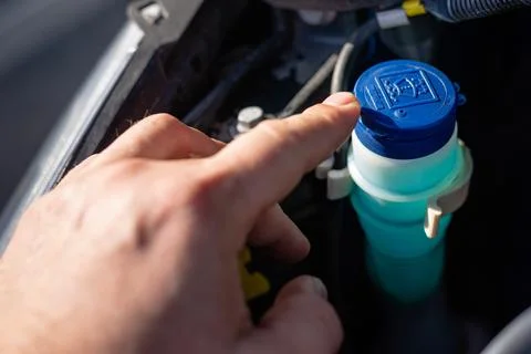 Hand opening blue cap of windshield washer reservoir Stock Photos