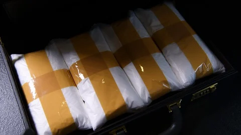A hand opening the briefcase and checking a pack of narcotic drugs 库存影片 129584874