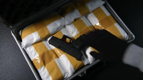 A hand opening the briefcase full of narcotic drugs with a gun Stock Footage 137694018