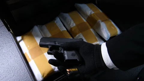 A hand opening the briefcase full of narcotic drugs with a gun Stock Footage 141980614