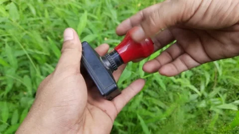 Hand Opening Cap of a Black Rubber Stamp in Grassy Background Stock Footage 309913999