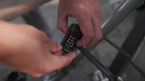 Hand opening coded bicycle segment lock on locked bicycle parked in cycle lot Stock Footage 236718933