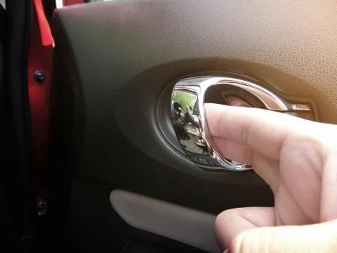 The hand is opening the door handle inside the car. Stock Photos