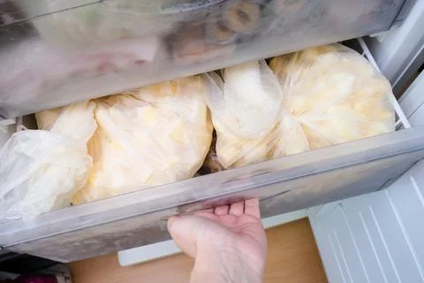 A hand opening a drawer of a freezer with frozen foods, vegetables, long-term Stock Photos