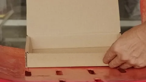 Hand opening empty small cardboard box on red surface Video stock 320128986