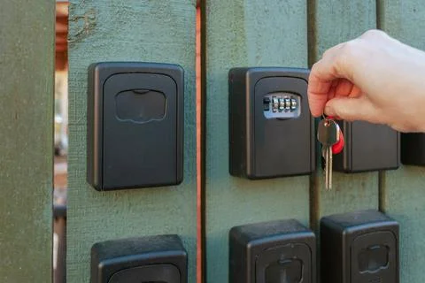 Hand opening key lock box on wooden fence Stock Photos