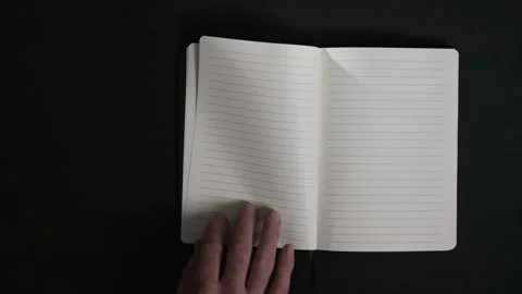 Hand opening notebook on black background Stock Footage 327288635