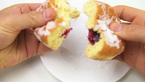 Hand opening one single powdered sugar donut on white plate macro Stock-Footage 169349080