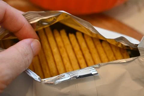 Hand opening a package of extruded crispbread Stock Photos