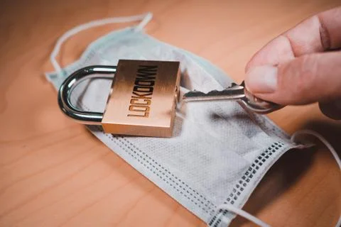 Hand opening a padlock over a face mask Foto stock