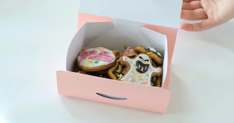Hand opening pink gift box and taking one black cat cookie out of cookies Video stock 81377150
