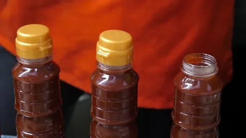 Hand opening a plastic bottle of spicy red Korean fish cake sauce for street foo Stock Footage 337374230