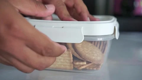 Hand opening a plastic container filled with crackers. Stock-Footage 347057943