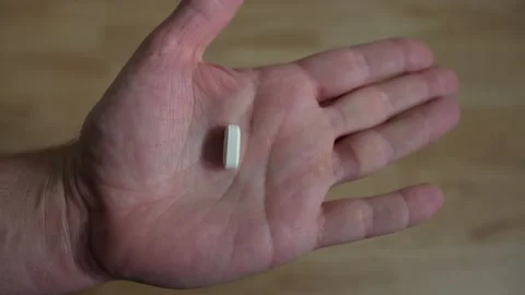 Hand opening up to reveal single white pill in man's hand, closeup 4k medication Stock Footage 136493733