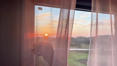 Hand Opening Roller Blind at Window Revealing Sunset View Stock Footage 345042239