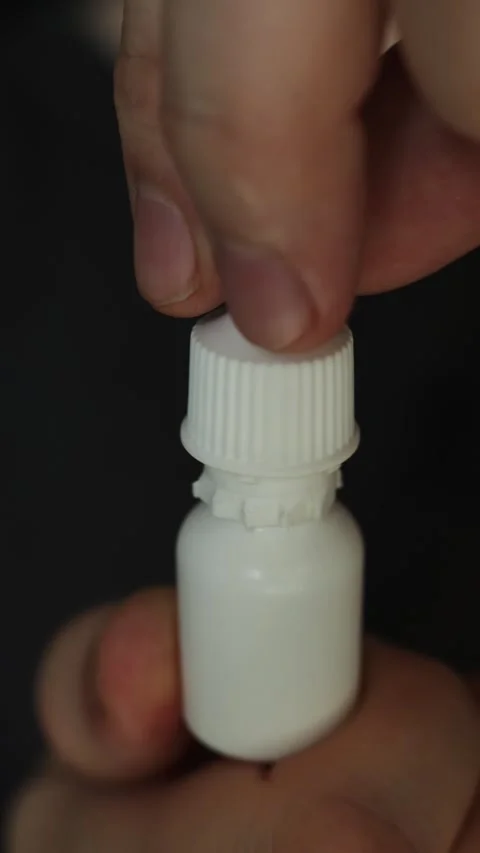 Hand opening a small white dropper bottle for medication or eye drops Stock Footage 340264206