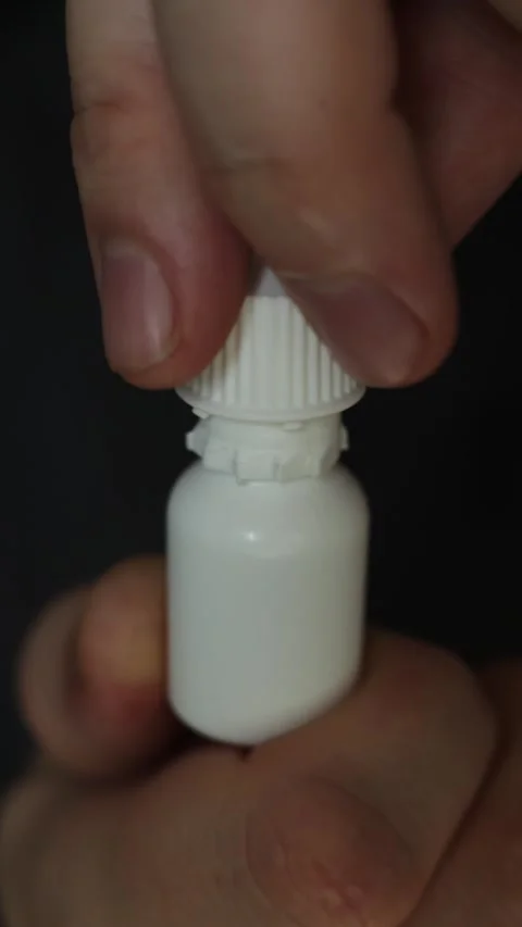 Hand opening a small white dropper bottle for medication or eye drops Stock Footage 340264290