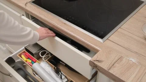 Hand opening white kitchen drawer below wooden countertop with built-in ele.. Stock Photos