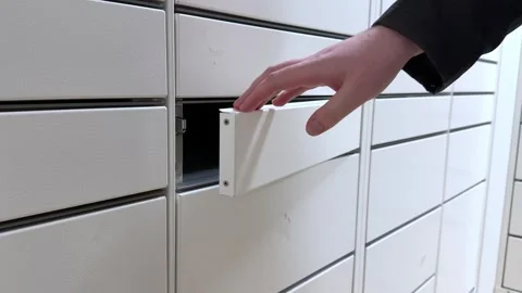 A hand opening a white metal locker compartment to retrieve stored items, Stock Footage 346466472
