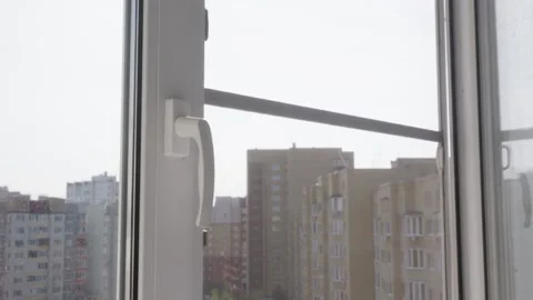 Hand opening white plastic window in apartment with urban view outside Stock Footage 318774662