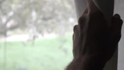 Hand opening window blind. peeking outside. moves the curtain to reveal Stock Footage 230970676